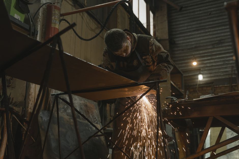 Welder working on a steel structure with sparks flying, building a barn frame
