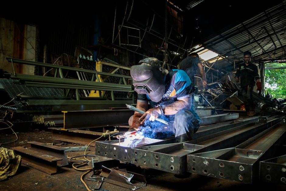 Welder cutting steel with sparks in a fabrication workshop